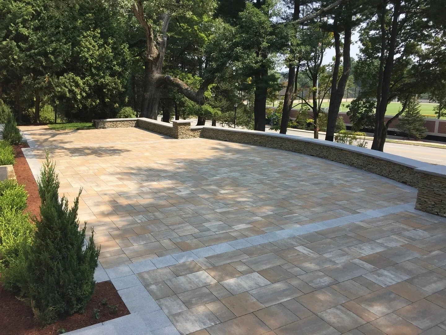Wide paved terrace bounded by a low curved wall.