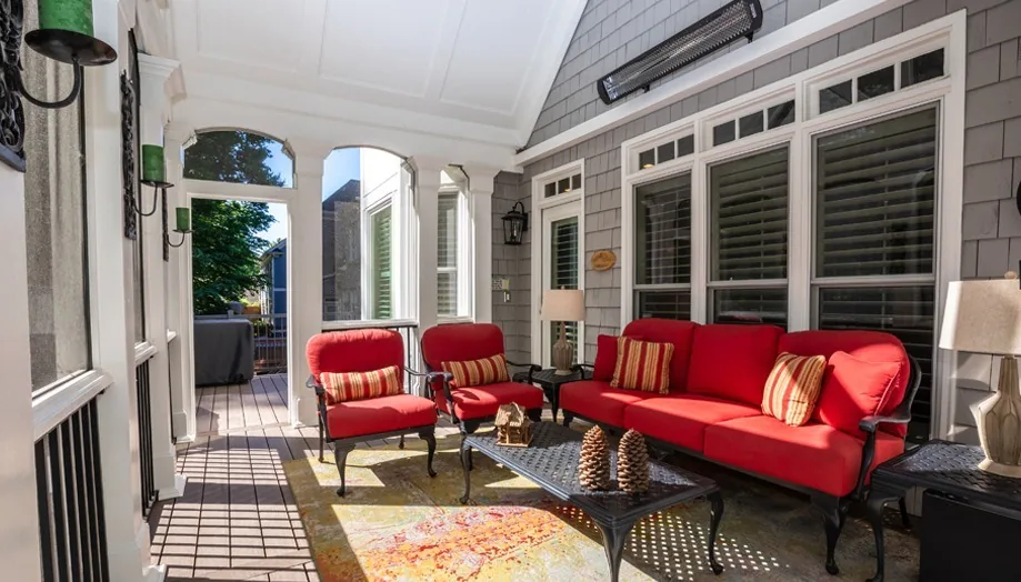 Screened porch furnished with red seating.