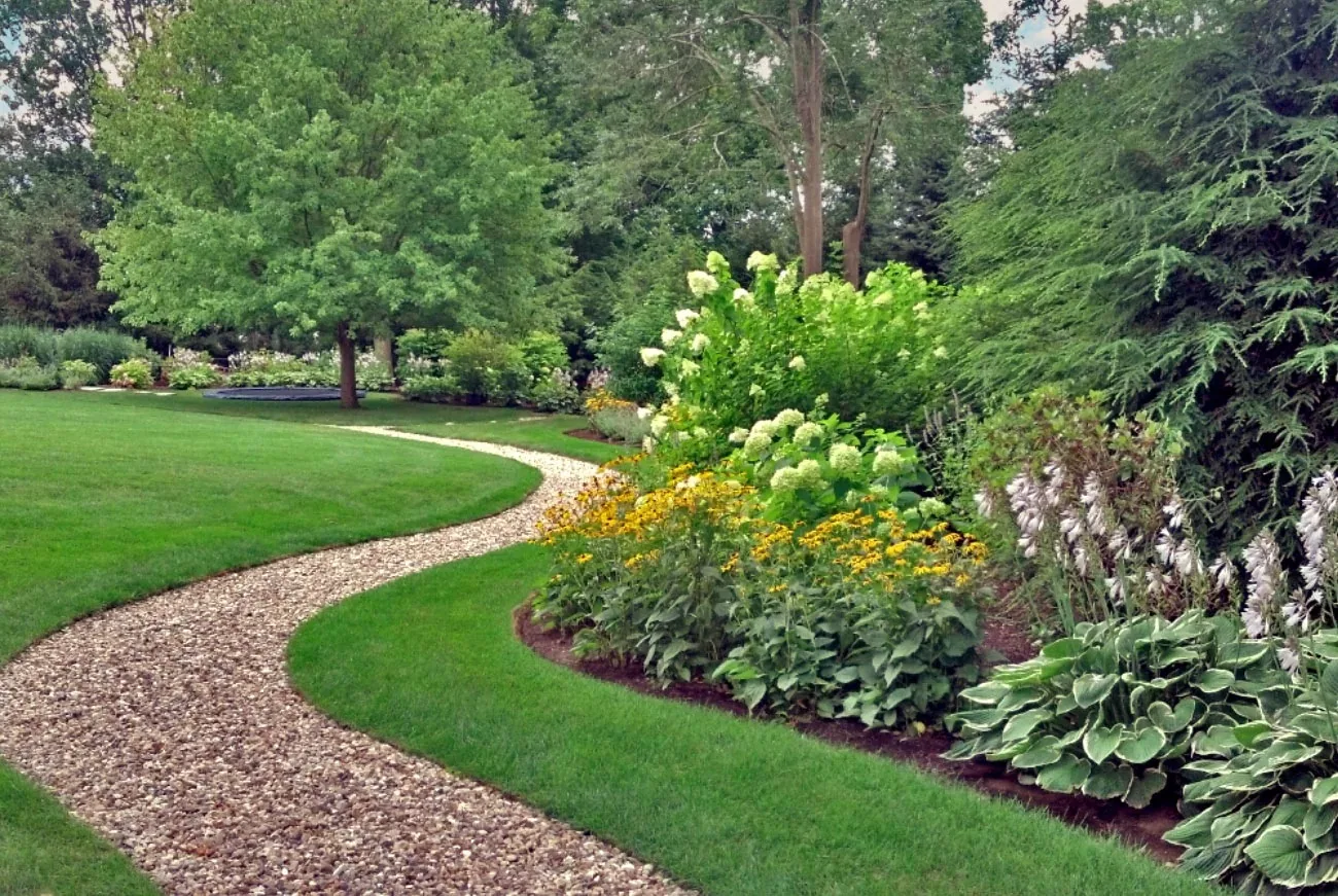 Curved gravel path between lawn and flowering borders.