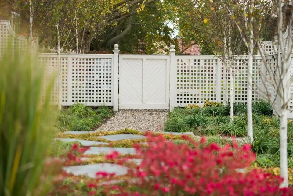 White garden gate beyond a planted path.
