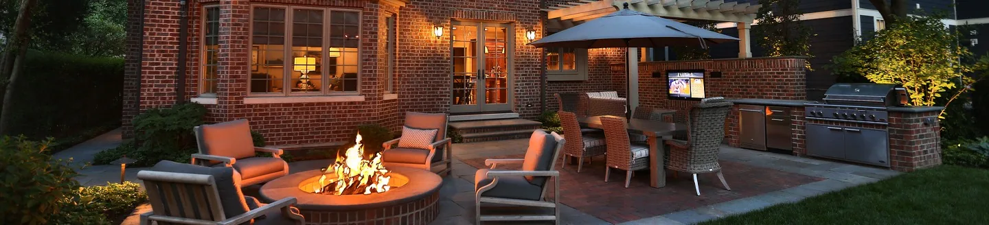 Covered outdoor media and cooking space at dusk.