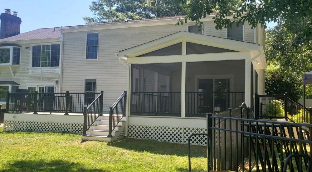 The screened porch and adjoining deck share a view across the fenced backyard.