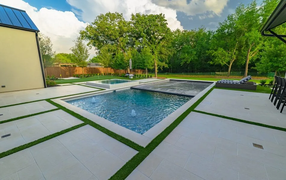 Rectangular pool and spa framed by pale paving panels and narrow green joints.