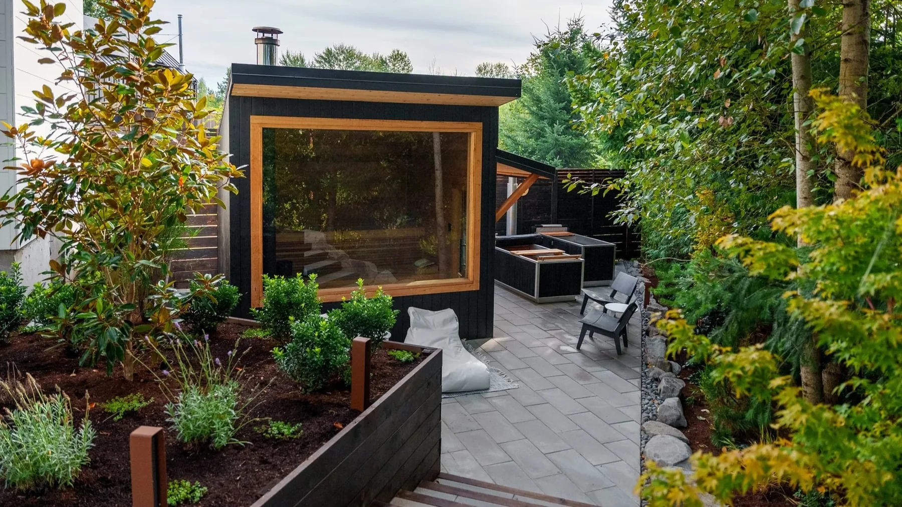 Glass-fronted sauna at the end of a planted path.