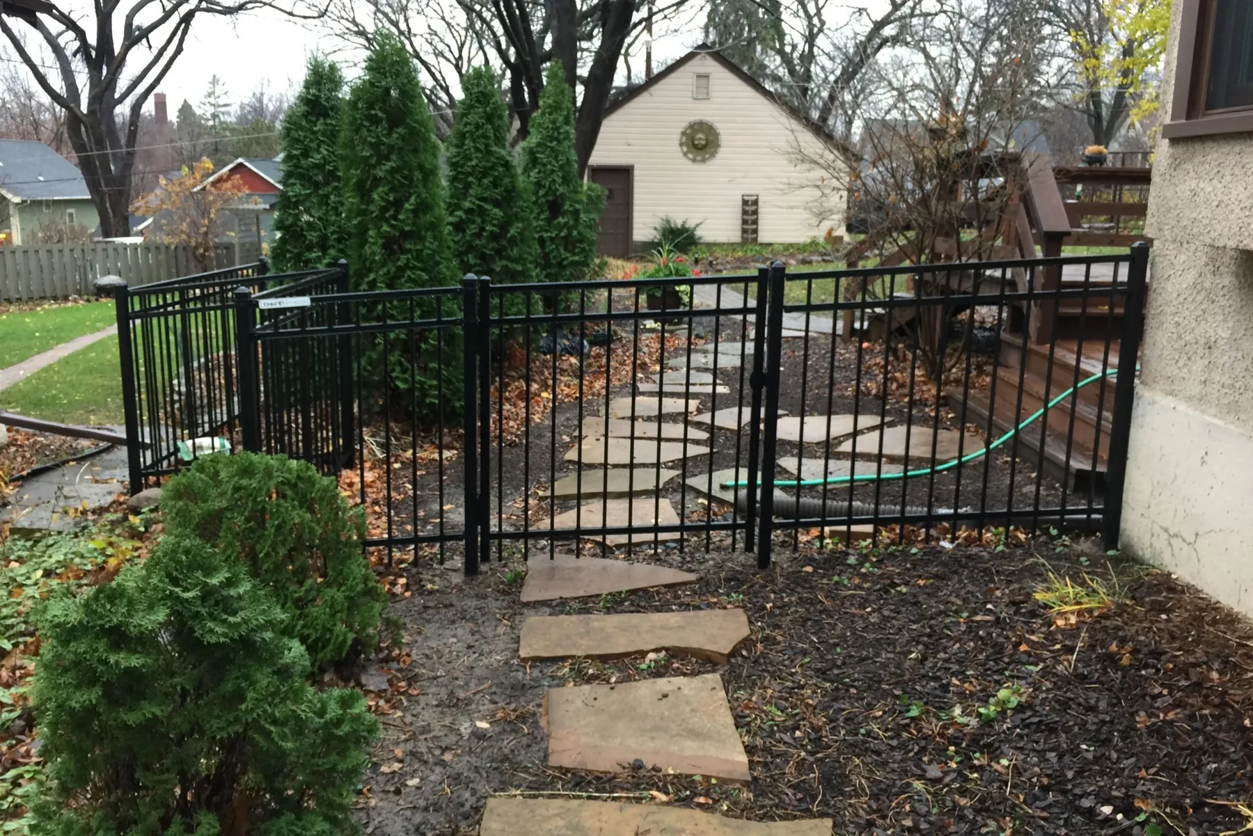 Dark metal gate at the end of a stepping-stone garden path.