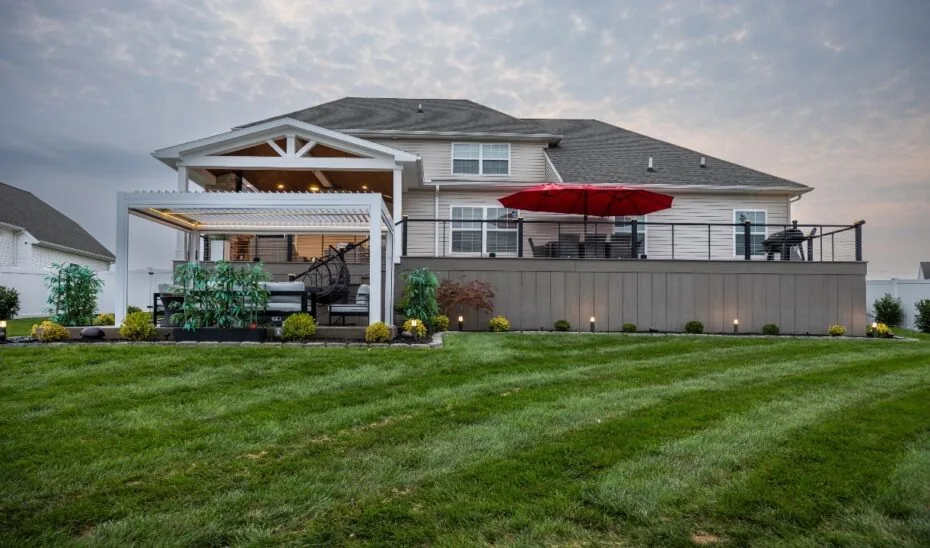 Covered porch, open deck and lower pergola beside a house.