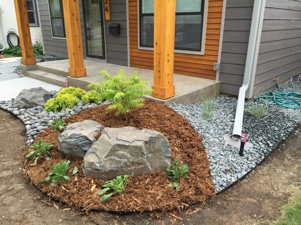 Stone path, boulder and planting beside timber porch posts.