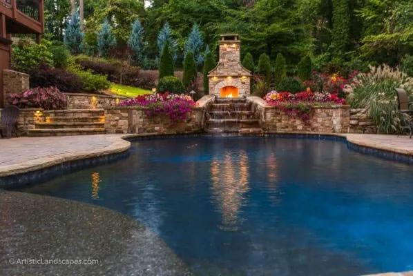 Curving pool facing a stone fireplace and planted terrace.